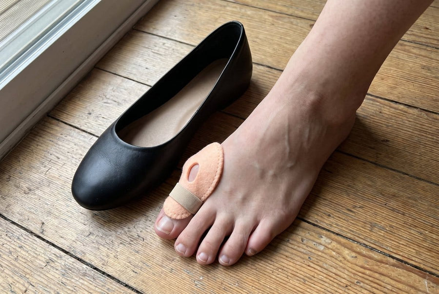 Bunion cushion worn over the big toe joint, next to a ballet flat
