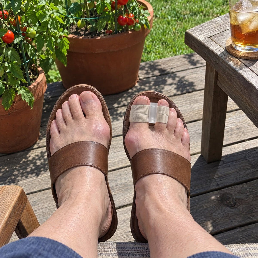 Feet in open sandals on a sunny patio, wearing Askelo